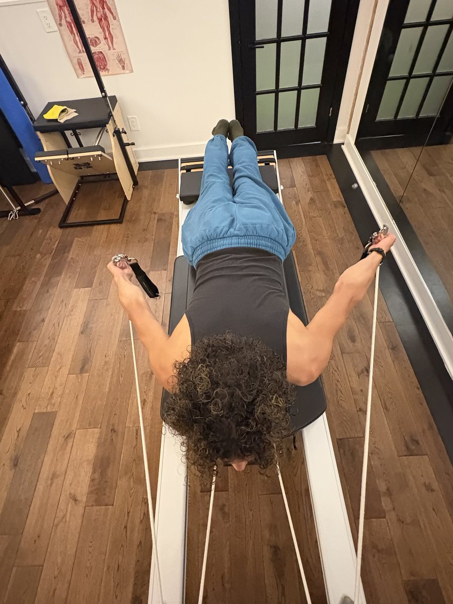 Feet in the straps on the reformer, seen from above, both hands on the handles